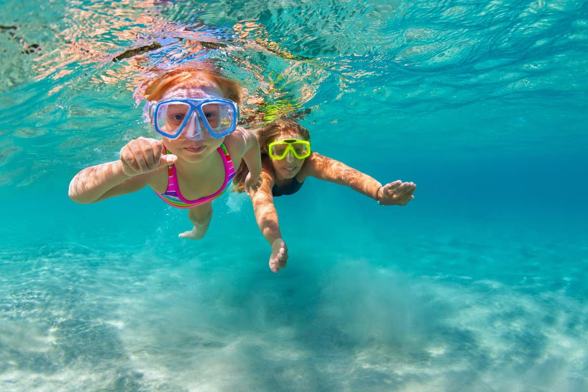Mother with child swim underwater with fun in sea